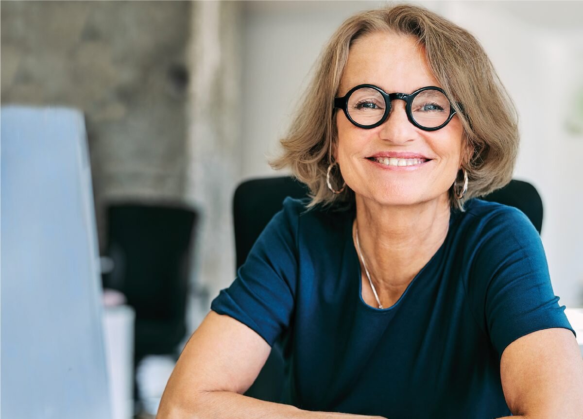Selbstbewusste Frau in den Wechseljahren am Arbeitsplatz